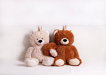 Children's toys - bears of brown and beige color with golden little crownsс are sitting on the sofa. Selective focus.