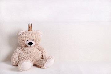 Children's toys - bears of brown and beige color with golden little crownsс are sitting on the sofa. Selective focus.