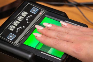 The process of scanning fingerprints during the check at border crossing. Female hand puts fingers to the fingerprint scanner. Biometric, identity verification and border control, immigration concept