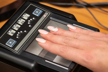 The process of scanning fingerprints during the check at border crossing. Female hand puts fingers to the fingerprint scanner. Biometric, identity verification and border control, immigration concept