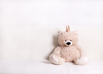 Children's toys - bears of brown and beige color with golden little crownsс are sitting on the sofa. Selective focus.