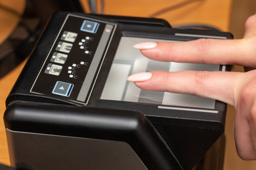 The process of scanning fingerprints during the check at border crossing. Female hand puts fingers to the fingerprint scanner. Biometric, identity verification and border control, immigration concept