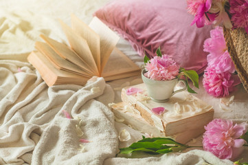 Still life details in home interior of living room. Cup with Pions flowers and spring decor on the books. Read, Rest. Cozy spring concept.