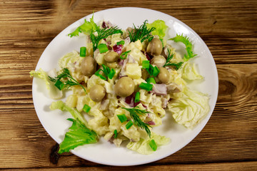 Potato salad with marinated mushrooms, eggs, red onion and mayonnaise on wooden table