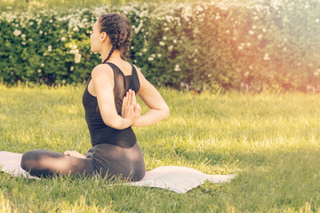 Fototapeta na wymiar Young Caucasian woman doing yoga in the Park. Sits with hands behind his back
