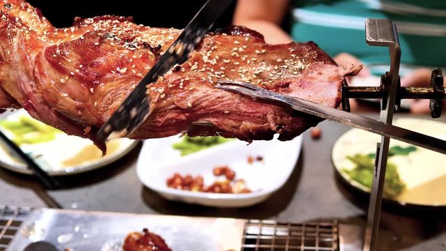 Waiter cuts roasted lamb leg for customer in restaurant, delicious food, 4k movie, slow motion.