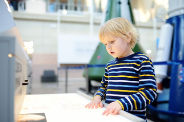 Little сaucasian boy is looking an exposition in a scientific museum