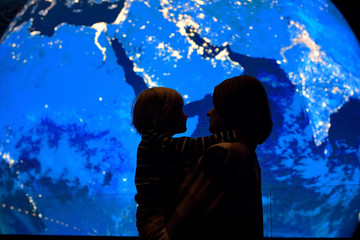 Silhouette of adult and child on background of globe earth