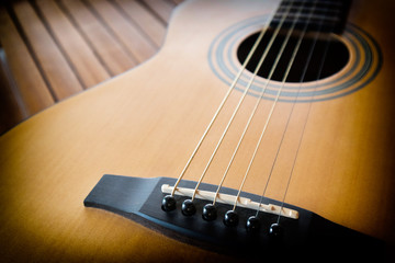 Obraz premium Acoustic guitar on a wooden background with copy space.The guitar is a fretted musical instrument that usually has six strings.