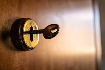 Old metal key inside the lock with the wooden door blurred background - Image