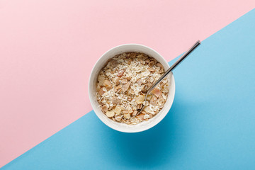 top view of breakfast cereal in bowl on blue and pink background