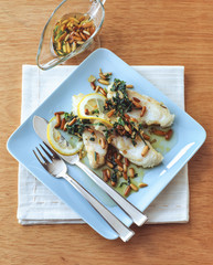 Fried fish fillet with roasted pine nuts served on the plate
