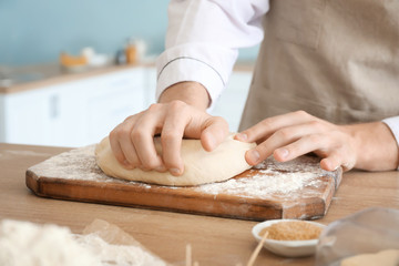 Chef kneading dough in kitchen, closeup