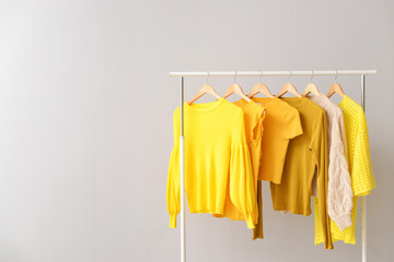 Rack with clothes after dry-cleaning on light background