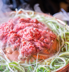 Beef barbecue bulgogi in Korean restaurant in Seoul, lifestyle fresh korean food cuisine on copper pan with sliced green onion, close up, copy space