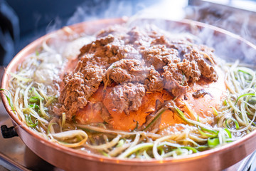 Beef barbecue bulgogi in Korean restaurant in Seoul, lifestyle fresh korean food cuisine on copper pan with sliced green onion, close up, copy space