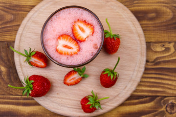 Glass of fresh strawberry smoothie on a wooden table. Top view