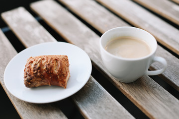 Coffee white cup, croissants on wooden table background. Breakfast concept. Freshly baked buns and coffee or cappuccino. Top view.