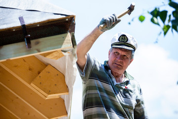 Carpenter working on the roof wooden structure - driving in big nail