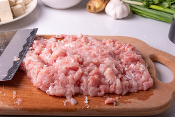 Minced meat and traditional Chinese knife Tsai Dao on a cutting board and ingredients for cooking Mapo doufu.