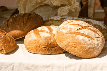 Large loaves of bread on a rustic background on a street counter.