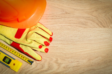 Protective hard hat, headphones, gloves, glasses and roulette on wooden background, copy space.