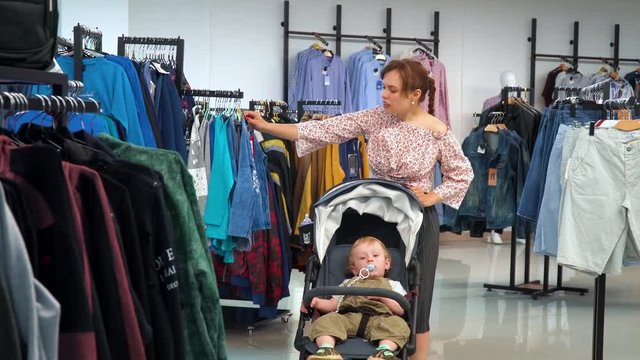 Beautiful girl with a child goes to the store and chooses clothes