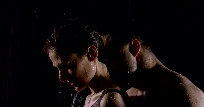 man is kissing neck and shoulders of his beloved girlfriend from back, standing under rain