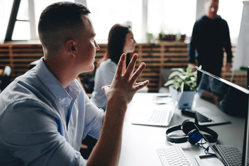 Staff meeting of a young successful team in the light modern office equipped with modern office equipment
