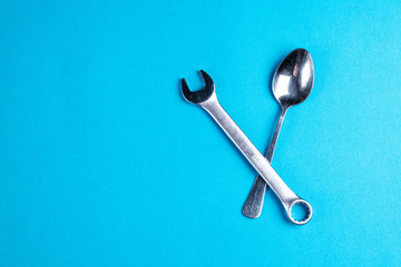 teaspoon and small wrench on blue background