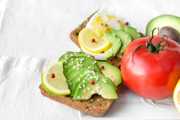 sandwich with avocado, lemon and sesame seeds, next to a red tomato