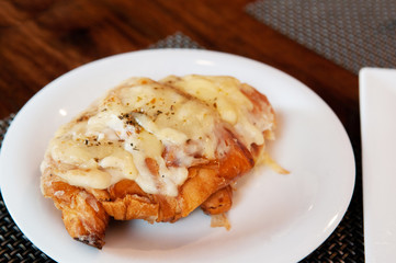 Baked pastry cheese croissant on white plate