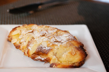 Baked pastry almond croissant on white plate