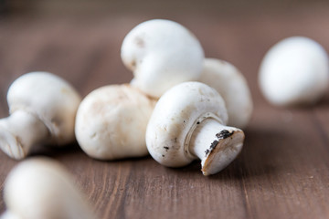 many fresh raw mushrooms on brown wood surface, champignons