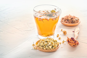 Herbal tea with pharmaceutical chamomile, dry chrysanthemum and hunters on a white table. Copy space