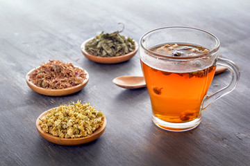 Herbal tea with pharmaceutical chamomile, dry chrysanthemum and hunters on a gray wooden table