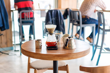 Closeup of coffee brewing gadgets on wooden table in cafe. Drip brewing, filtered coffee, or pour-over is a method which involves pouring water over roasted, ground coffee beans contained in a filter