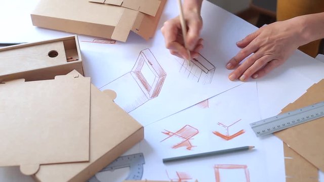 Designer draws a mockup for crafting cardboard box. Development of packaging design sketch.