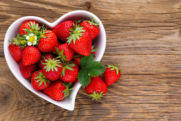 Strawberry heart. Fresh strawberries in plate on white wooden table. Top view, copy space.