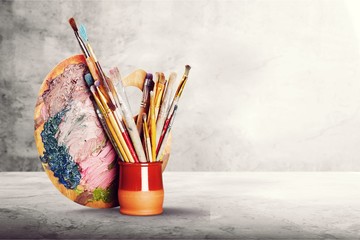 Brushes in glass jar on wooden desk