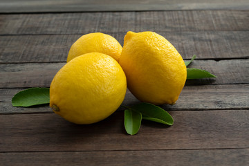 fresh lemons with leaves on wooden table