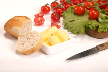 Ripe fresh Juicy organic brunch of cherry tomatoes on cutting board with Green Lettuce, bread, butter on a white table