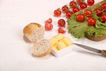 Ripe fresh Juicy organic brunch of cherry tomatoes on cutting board with Green Lettuce, bread, butter on a white table