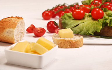 Ripe fresh Juicy organic brunch of cherry tomatoes on cutting board with Green Lettuce, bread, butter on a white table