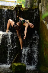 Fototapeta premium Young brunette model posing against a waterfall