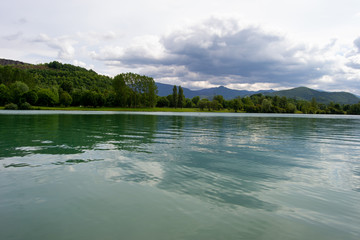 Beautifull cloudy landscape on a lake with reflections and mountains in the horizon