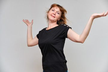 Studio portrait of a beautiful pretty woman aged 40 years on a white background, smiling, showing different emotions, happy with life. In a black sweater with red hair. Directly opposite the camera.