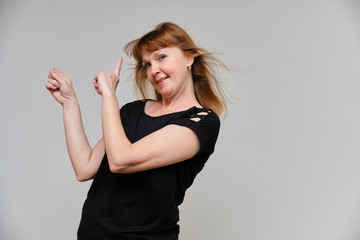 Studio portrait of a beautiful pretty woman aged 40 years on a white background, smiling, showing different emotions, happy with life. In a black sweater with red hair. Directly opposite the camera.