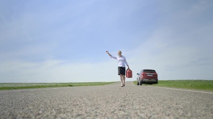 woman with canister trying to stop car waving his hand on road. Blurred background. girl gives sign of hitchhiking. - Powered by Adobe
