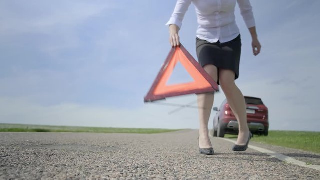 Woman removes warning triangle from car road. Close-up, blurred background. traffic sign.